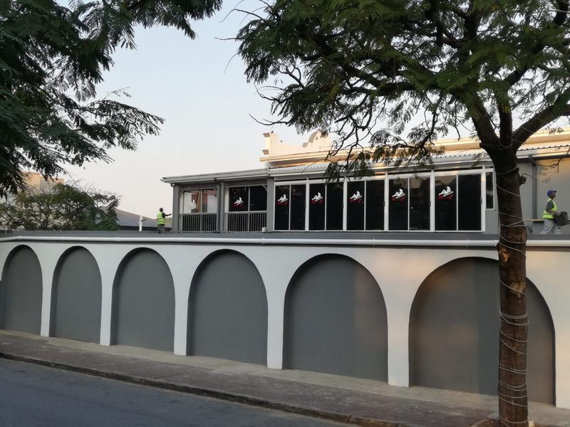 A completed building with an arched colonnade below a glazed frontage.