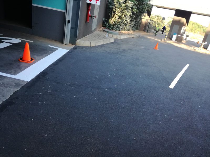 Freshly laid asphalt with new white line markings and traffic cones.