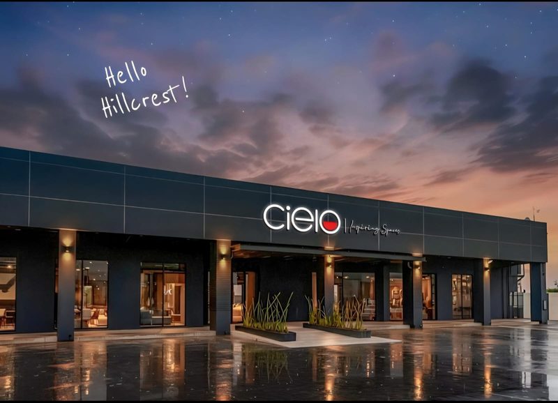 A completed retail centre lit up at dusk with its signage on.
