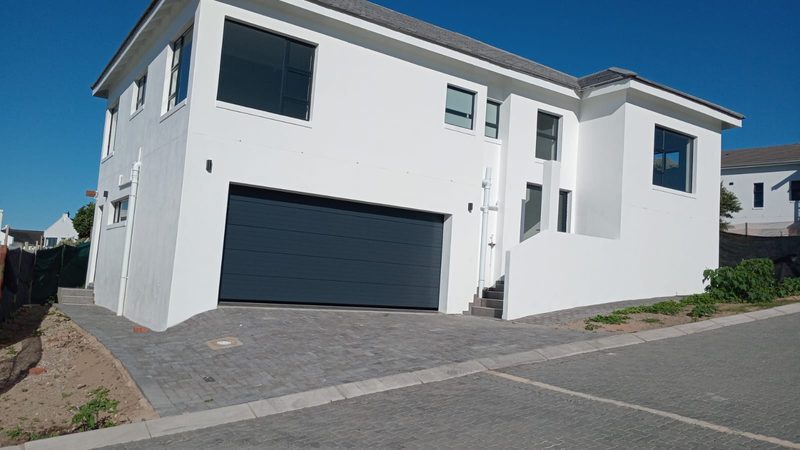 A completed white double-storey home with a paved driveway.