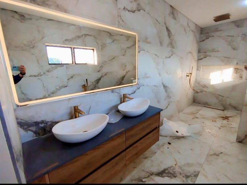 Twin basins on a timber vanity below a backlit mirror.