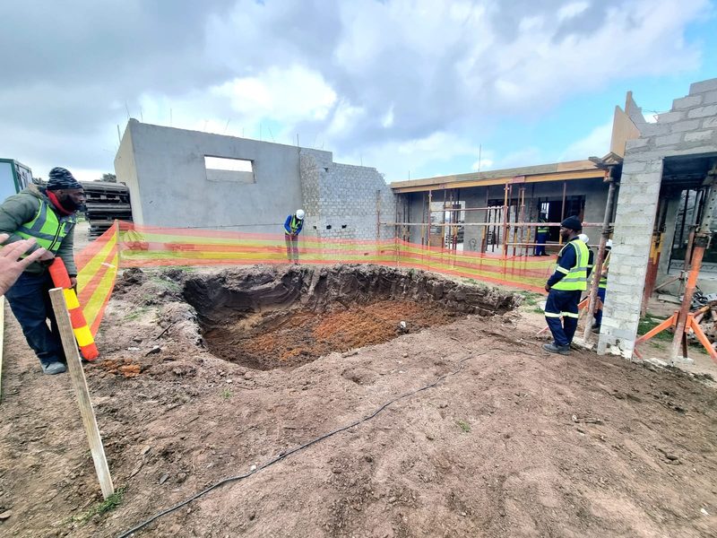 A crew setting out and excavating foundations beside new block walls.