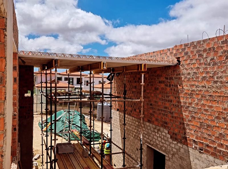Face brick walls under construction with scaffolding to the upper level.