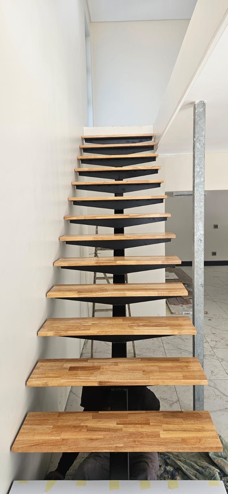 A floating timber staircase with cantilevered treads against a white wall.