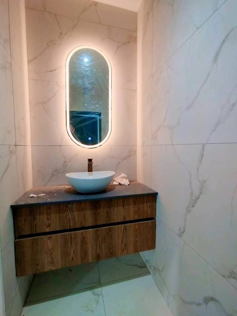 A guest cloakroom with a floating timber vanity and backlit oval mirror.
