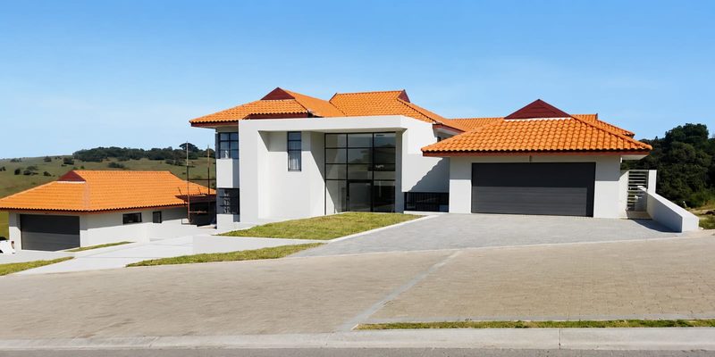 A completed modern home with a terracotta tiled roof and finished driveway.