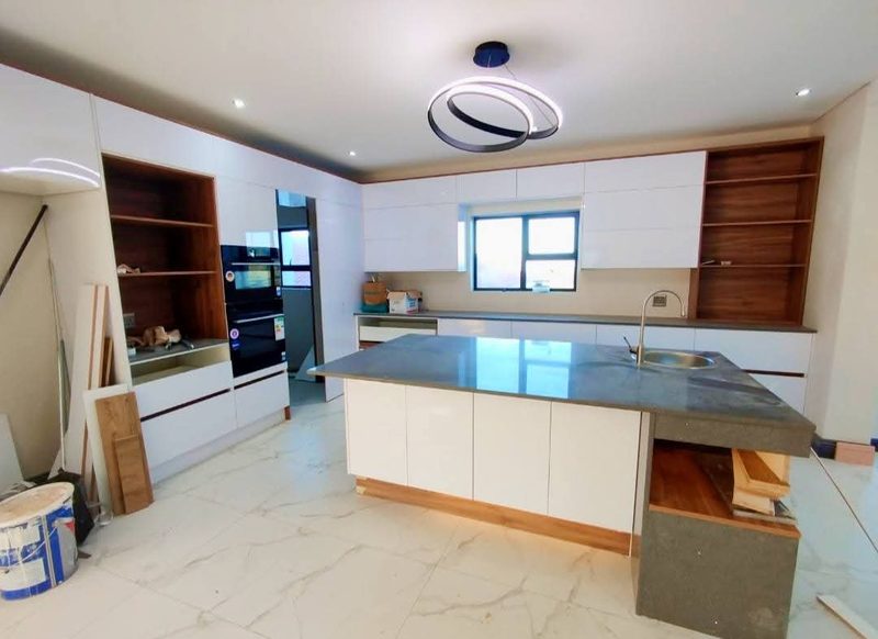 A fitted kitchen with a large stone-topped island and white joinery.