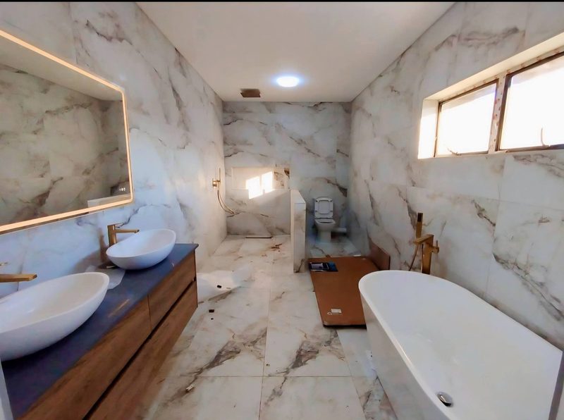 A marble-tiled en-suite with a freestanding bath and twin basins.
