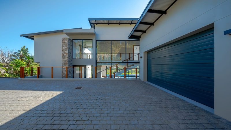 A modern double-storey home with stone cladding and a paved driveway.