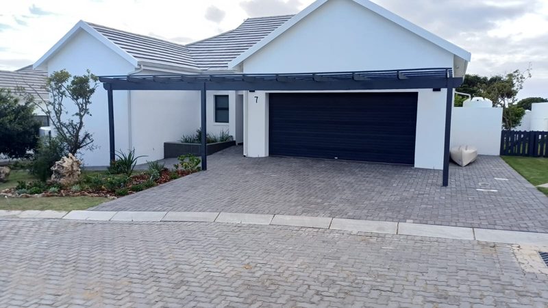 A home with a timber pergola carport over a paved driveway.