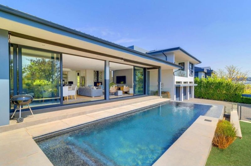 A modern home with stacking doors open onto a pool terrace.