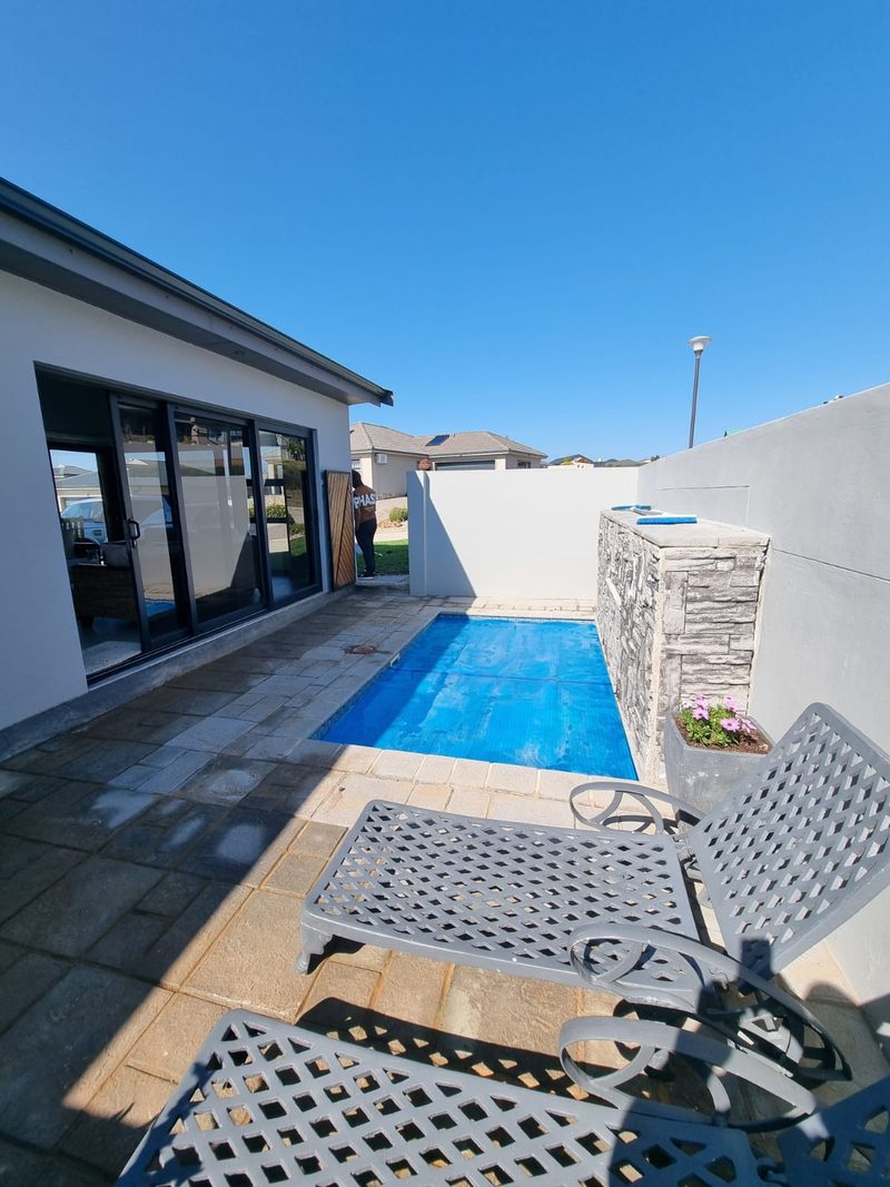 A pool and paved terrace outside a home with stacking doors.