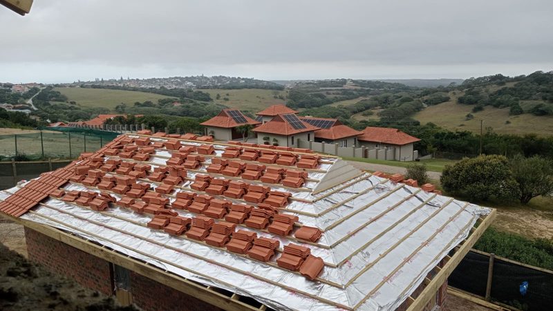 Roof tiles being laid over battens and underlay, seen from above.