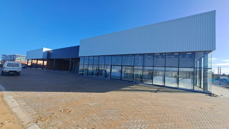 A completed commercial showroom with full-height glazing and paved forecourt.