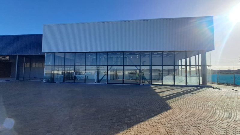 A large new commercial building with full-height glazed shopfronts.