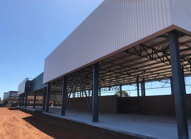 A steel-framed covered canopy alongside an industrial building.