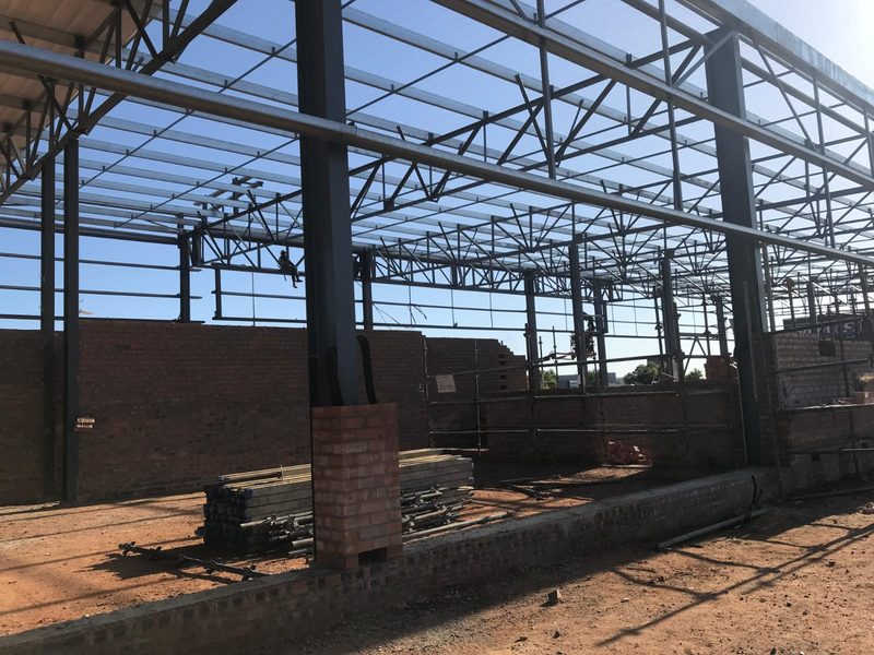 Brick infill walls being built inside an erected steel portal frame.