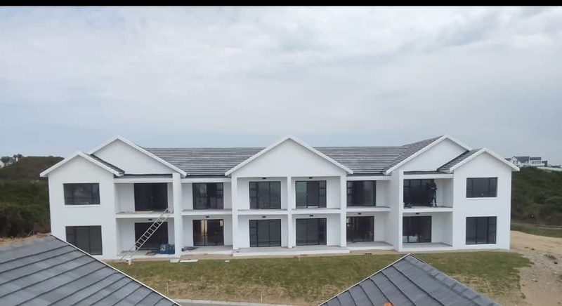 A row of completed white townhouses with pitched roofs.